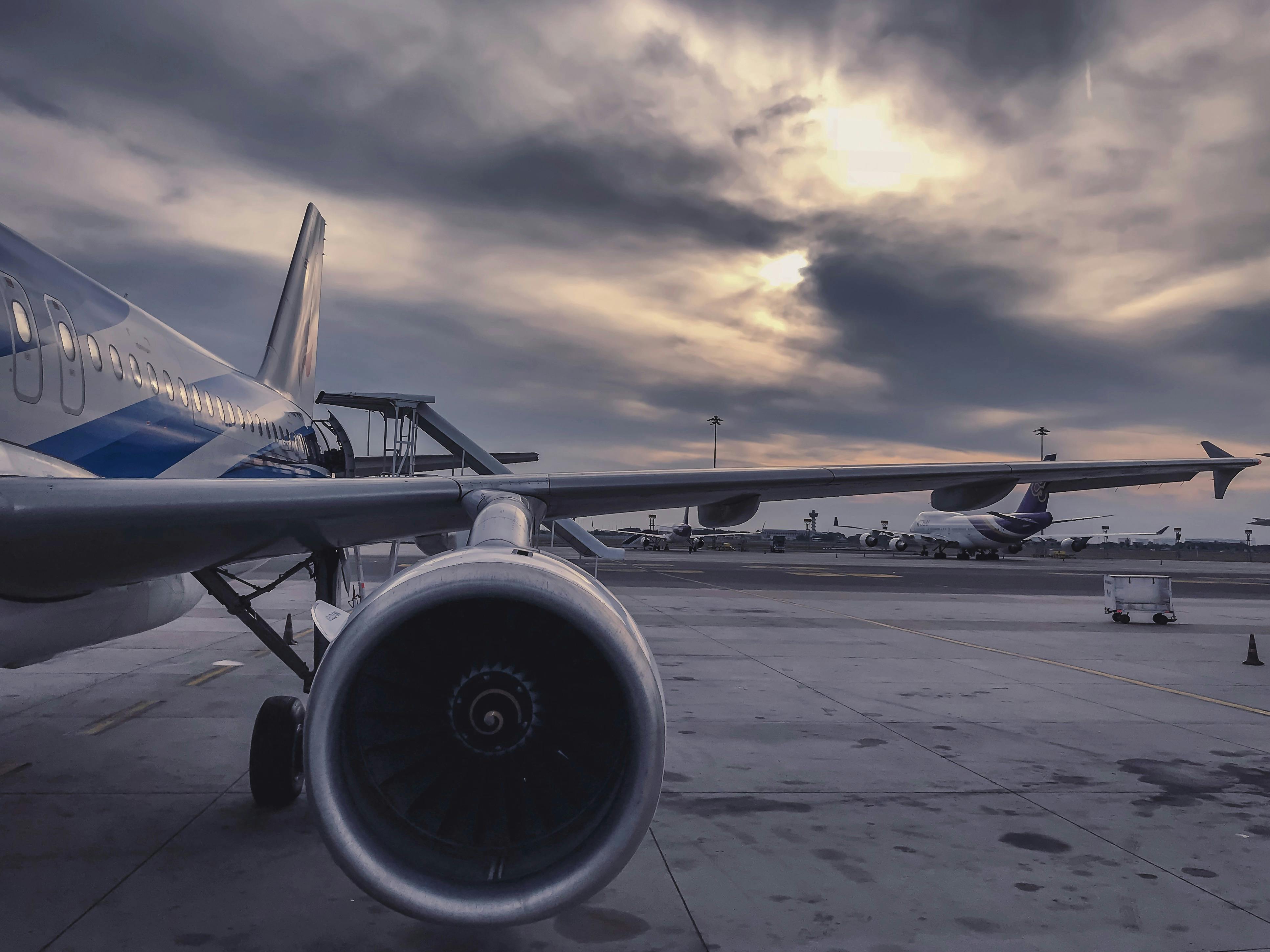 Asa de um avião voando acima das nuvens durante o pôr do sol.